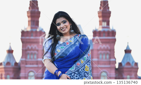 Bangladeshi girl smiling in Moscow, wearing a saree in front of a landmark building 135136740
