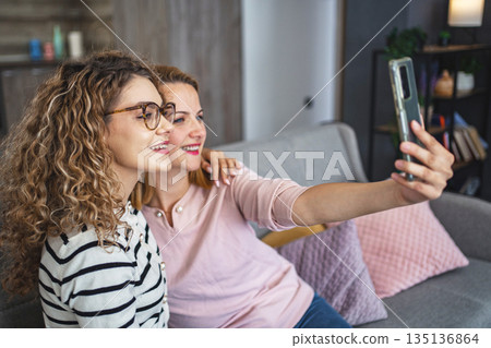 Two Women Sitting on a Couch Taking a Selfie Two Women Sitting on a Couch Taking a Selfie 135136864