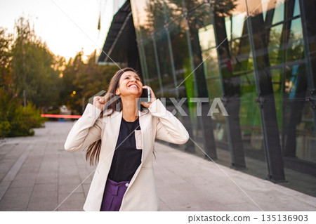 Businesswoman talking on a phone after work 135136903