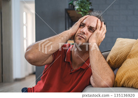 Man sitting alone at home looking sad and distraught Man sitting alone at home looking sad and distraught 135136920