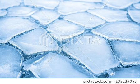 Floating blocks of ice create a captivating geometric pattern on the surface of a freezing lake, forming a stunning natural mosaic that showcases the beauty of winter 135137052