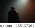 Lonely Hooded Figure in Silhouette Under Spotlight, Quiet Contemplation in Night Mood 135137361