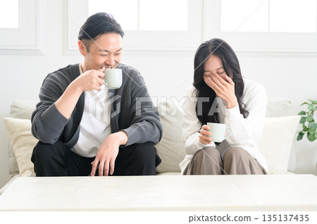 A man and a woman sitting on a sofa in the living room and having a conversation 135137435