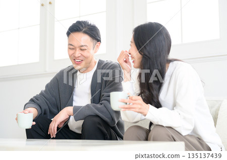 A man and a woman sitting on a sofa in the living room and having a conversation 135137439