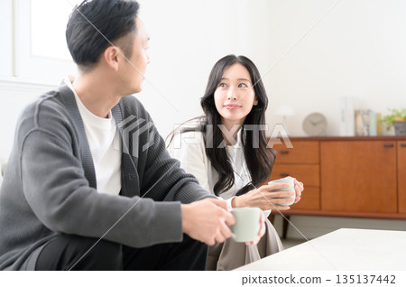 A man and a woman sitting on a sofa in the living room and having a conversation 135137442