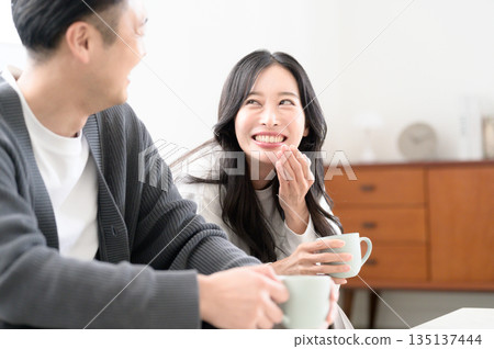 A man and a woman sitting on a sofa in the living room and having a conversation 135137444