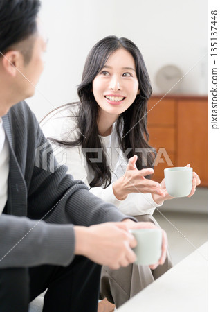 A man and a woman sitting on a sofa in the living room and having a conversation A man and a woman sitting on a sofa in the living room and having a conversation 135137448