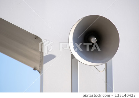 Megaphone-type speaker installed on an outdoor wall 135140422