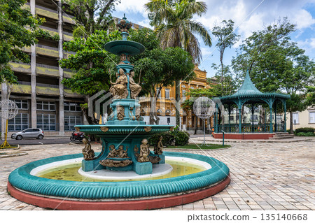 Fountain at Praca Dom Pedro II square in Manaus, Brazil on a Sunny Day with Mosaic Pavement and Lush Trees Fountain at Praca Dom Pedro II square in Manaus, Brazil on a Sunny Day with Mosaic Pavement and Lush Trees 135140668