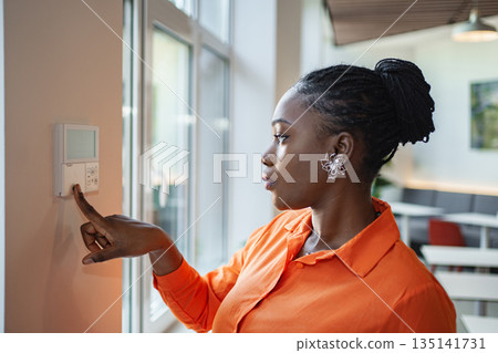 Woman Pointing at Light Switch on Wall 135141731