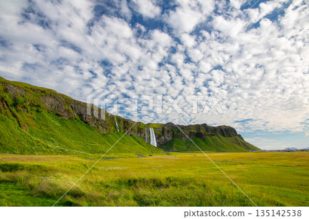 塞里雅蘭瀑布 (Seljalandsfoss) 從塞里雅蘭河 (Seljalandssá River) 傾瀉而下，映襯著冰島蔚藍天空中的層層疊疊的雲朵。 135142538