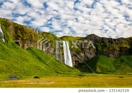 塞里雅蘭瀑布 (Seljalandsfoss) 從塞里雅蘭河 (Seljalandssá River) 傾瀉而下，映襯著冰島蔚藍天空中的層層疊疊的雲朵。 135142539