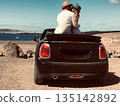 Romantic couple traveling by convertible car near ocean 135142892
