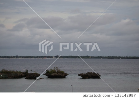 A view from Cebu Island with a cloudy sky, the opposite coast, small islands and rippling sea 135142997