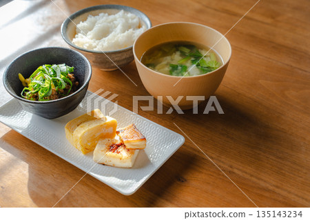 簡單的日式早餐,米飯和味噌湯,擺放在木桌上。 簡單的日式早餐,米飯和味噌湯,擺放在木桌上。 135143234