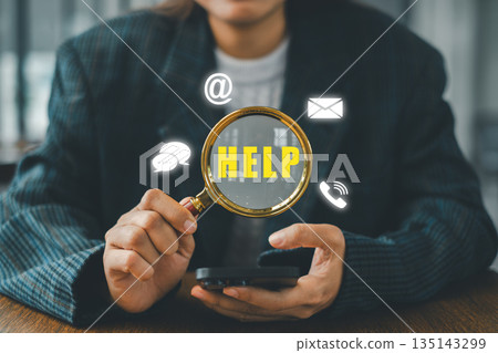 Businesswoman holding a magnifying glass over help icons, symbolizing communication and support in a digital environment. Businesswoman holding a magnifying glass over help icons, symbolizing communication and support in a digital environment. 135143299