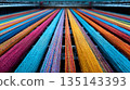 Close-up of multicolored threads running parallel in a textile loom. The bright spectrum of colors creates a vibrant and textured pattern, highlighting the weaving process. 135143393