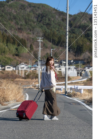 A young woman pulling a carry-on suitcase 135143451