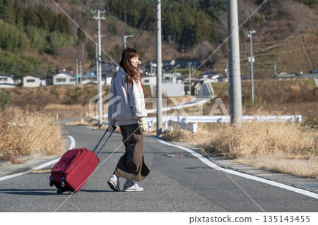 A young woman pulling a carry-on suitcase 135143455