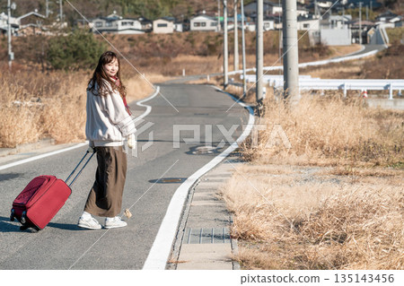 A young woman pulling a carry-on suitcase A young woman pulling a carry-on suitcase 135143456