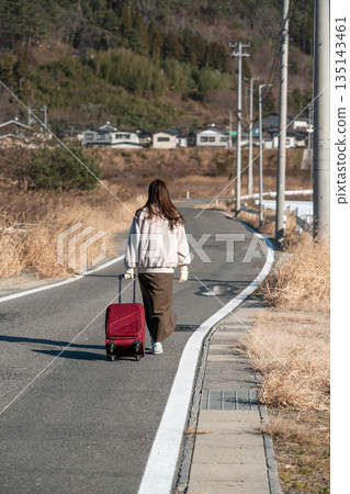 A young woman pulling a carry-on suitcase 135143461