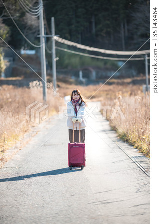 A young woman pulling a carry-on suitcase A young woman pulling a carry-on suitcase 135143464