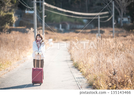 A young woman pulling a carry-on suitcase A young woman pulling a carry-on suitcase 135143466