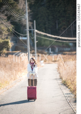 A young woman pulling a carry-on suitcase A young woman pulling a carry-on suitcase 135143467