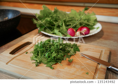 A bunch of red radishes are displayed on a green leaf. The radishes are fresh and ready to be eaten 135143492
