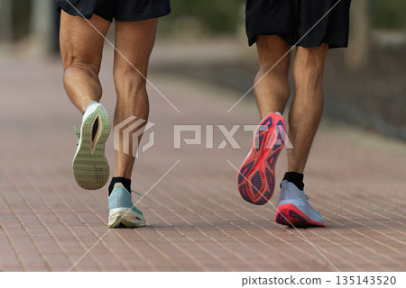 Two men running on the sidewalk, training for a marathon Two men running on the sidewalk, training for a marathon 135143520