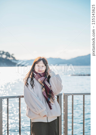 年輕女子站在海灘上 年輕女子站在海灘上 135143625