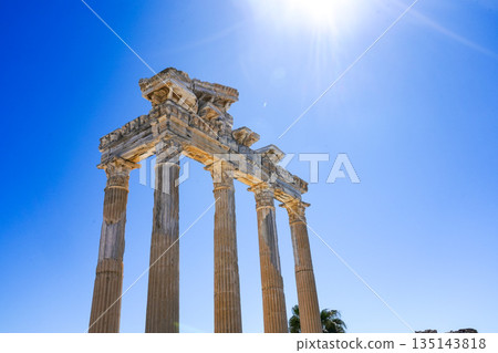 Ancient Columnar Structure Beneath a Vibrant Blue Sky with Sunlight Illuminating the Historic Architecture and Captivating Nature Surrounding It Ancient Columnar Structure Beneath a Vibrant Blue Sky with Sunlight Illuminating the Historic Architecture and Captivating Nature Surrounding It 135143818