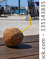 Refreshing Coconut Drink with a Yellow Straw Amidst a Beautiful Beachside Setting Under Clear Blue Skies 135143835