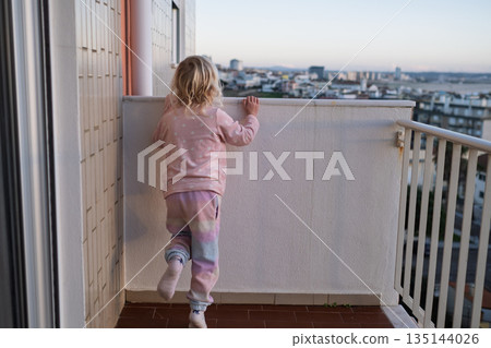 Little Girl Standing on Balcony Looking at City, Danger of Leaving Child Alone 135144026