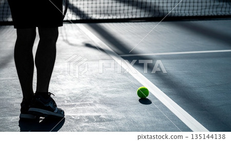 tennis scene with player shadow and a single ball resting on the court line, capturing tension, focus, anticipation, solitude, and decisive moment before serve in competitive sport 135144138