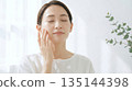Profile of a woman using cotton pads to do skin care in front of a mirror 16:9 135144398