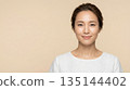 A clean-cut woman's frontal smile against a beige background 16:9 135144402