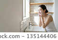 A young Japanese woman smiling and enjoying skin care while washing her face with foam in the bathroom in the morning 135144406