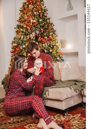 Family celebrates Christmas in matching pajamas at home Family celebrates Christmas in matching pajamas at home 135144427