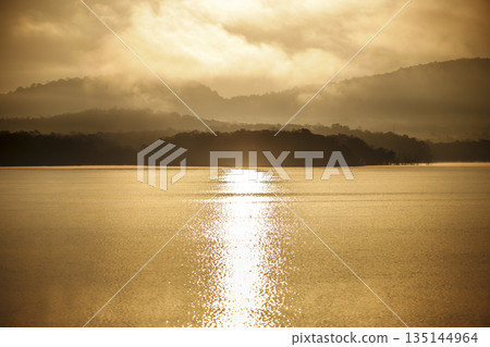 The quiet lake reflects the fading daylight and surrounding mountain forms The quiet lake reflects the fading daylight and surrounding mountain forms 135144964