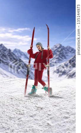 Confident design of woman standing with skis on snowy mountain ridge. 135144973