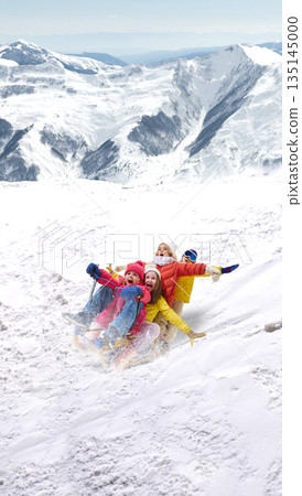 Energetic artwork of happy children sledding downhill in mountains. 135145000