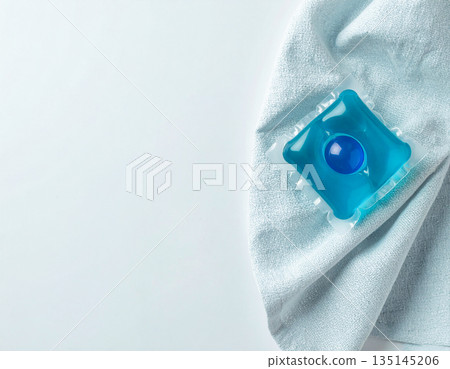 Gel laundry capsule in household. Soluble laundry detergent capsule on a neutral linen cloth with empty space for text. 135145206