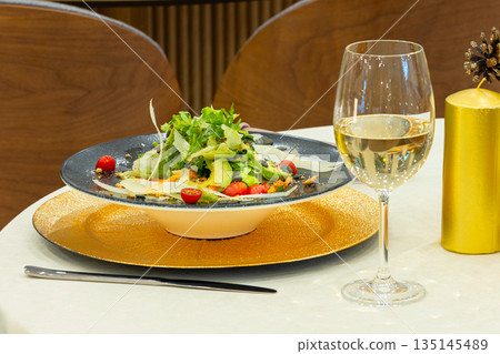Green salad and wine served on table in restaurant Green salad and wine served on table in restaurant 135145489