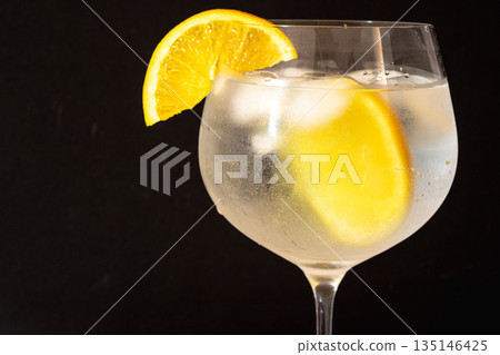 Gin tonic cocktail with orange slice and ice . Copy space.Black background 135146425