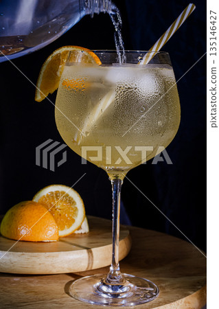 Pouring fresh gin cocktail with orange and ice 135146427
