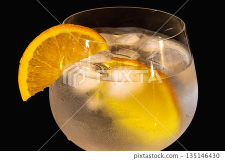 Side view of gin tonic cocktail with orange slice and ice on Black background 135146430
