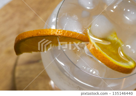 Top view of Gin tonic cocktail with orange slices and ice cubes on wooden background Top view of Gin tonic cocktail with orange slices and ice cubes on wooden background 135146440