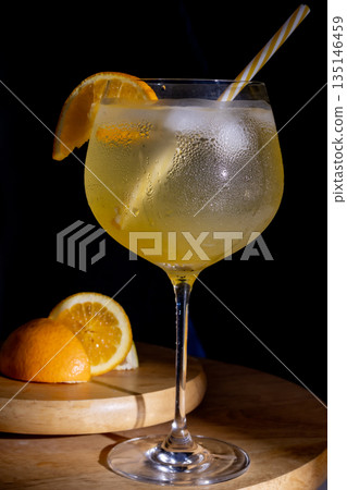 Gin tonic cocktail with fresh orange and ice in large glass. Gin tonic cocktail with fresh orange and ice in large glass. 135146459
