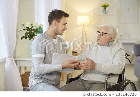 Handicapped old man in wheelchair gets psychological physical support from male nurse Handicapped old man in wheelchair gets psychological physical support from male nurse 135146726